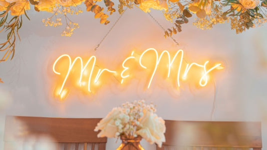 Neon yellow 'mr & mrs' wedding text LED sign with flower arrangement