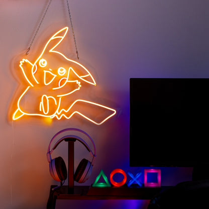 Yellow Pikachu LED neon sign hanging on a wall beside a desktop monitor